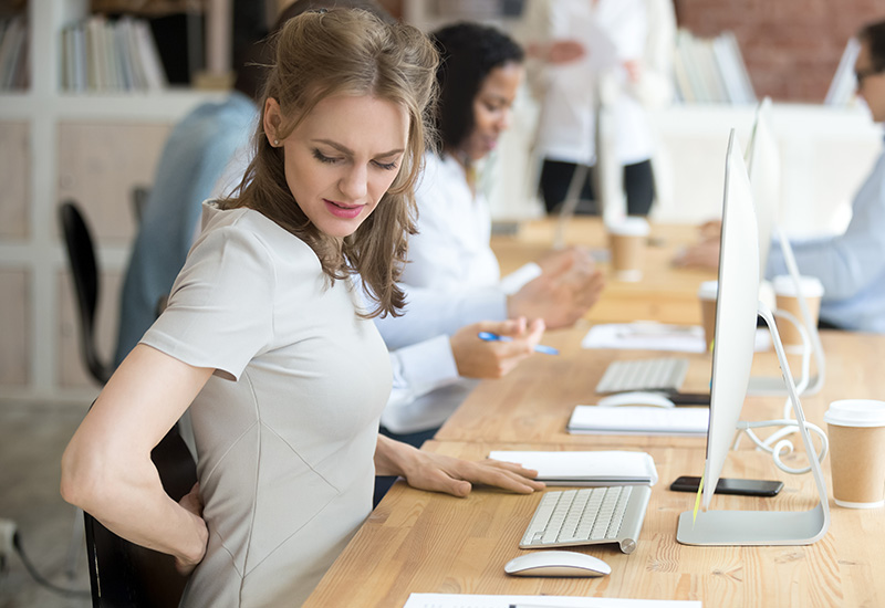 Image of a woman sitting at a desk with back pain