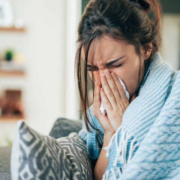 Woman blowing her nose sick at home