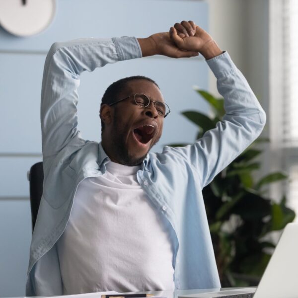 Black man yawning at his desk