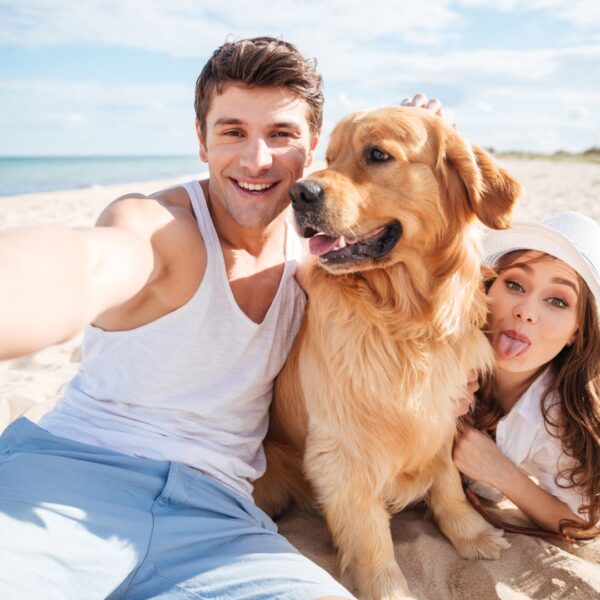 Happy man with woman and dog on beach