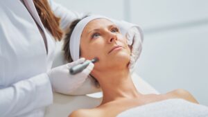 Woman looking serious while getting microneedling done near her jaw.
