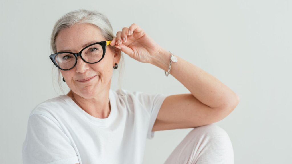 middle age woman in white room sits and hold glasses