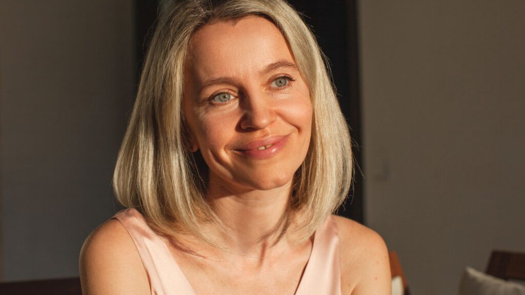 woman with shoulder length hair smiles in sunshine
