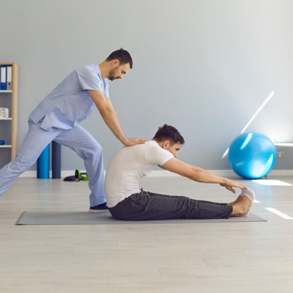 physical therapist helping man touch his toes