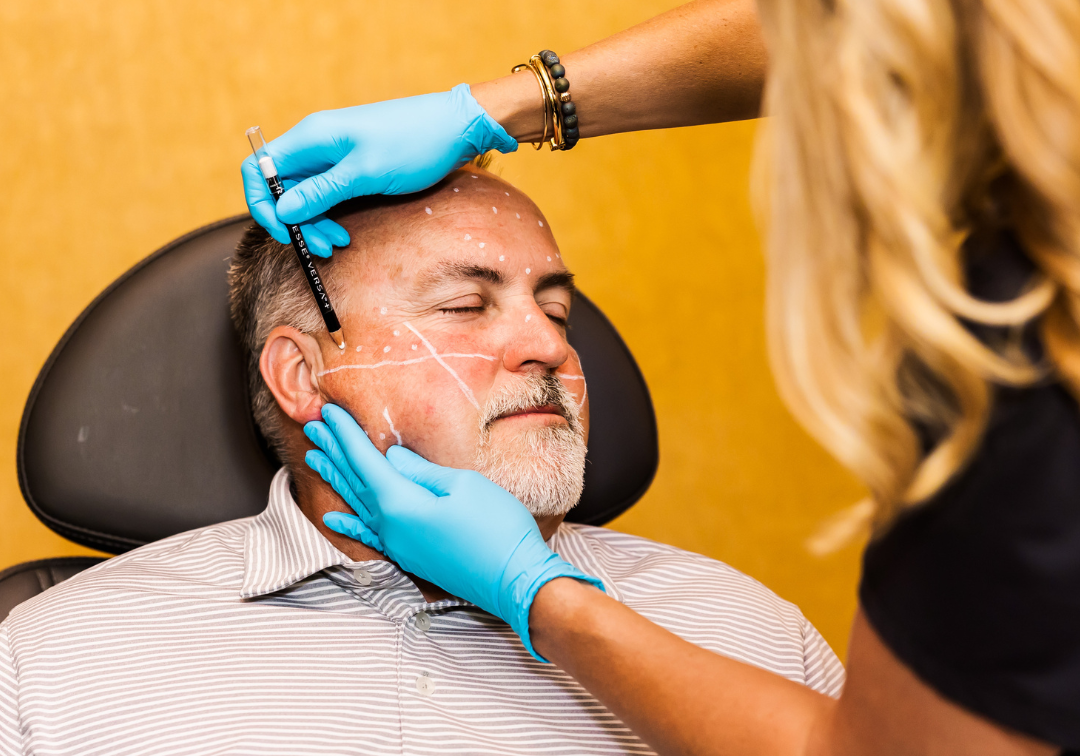 woman marking man's temple to receive a cosmetic injectable treatment